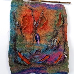 Puede incluir: Un tapiz de pared abstracto colorido hecho de lana fieltro. La pieza presenta una variedad de colores, incluyendo naranja, verde, azul y morado. La lana es texturizada y tiene una calidad tridimensional. La pieza está colgada de una varilla de madera.