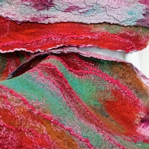 May include: A felted textile featuring a textured surface with layered colors including vibrant red, deep orange, teal green, and magenta. The material displays wavy, raised lines of fiber that create a dimensional, organic pattern across the fabric.