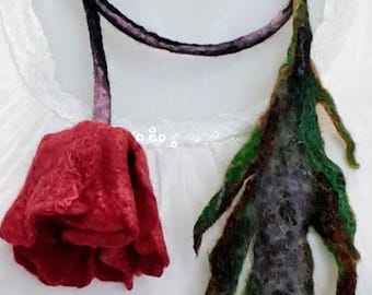Può includere: Una collana di lana feltrata con una rosa rossa e un ciondolo a forma di foglia verde e nera.
