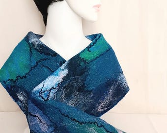 May include: A felted scarf featuring a textured abstract pattern in shades of deep teal, navy blue, and forest green. The scarf has a layered, uneven surface with thin, dark, meandering lines and lighter white fiber accents throughout the fabric.