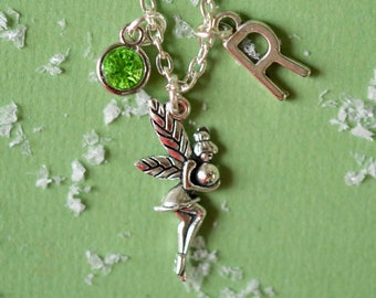 May include: Silver necklace with a green crystal charm, a fairy charm, and a letter "R" charm.