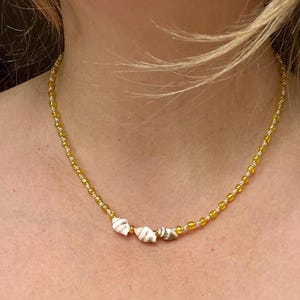 Delicado collar de conchas marinas con cuentas de semillas amarillas, blancas y doradas