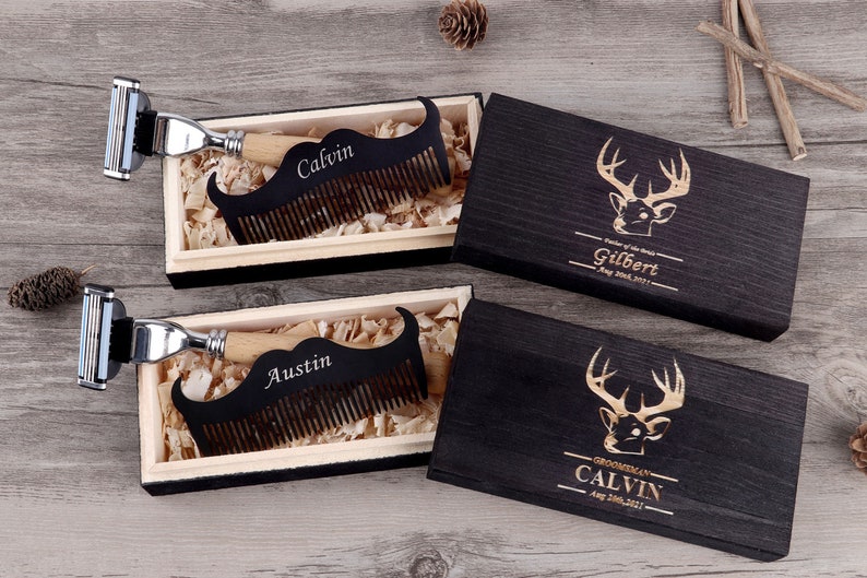 May include: A set of personalized grooming gifts. Each set includes a wooden mustache comb with a name engraved, a razor, and a wooden box with a deer head design. The boxes are black with gold lettering. The combs are black with a wooden handle.