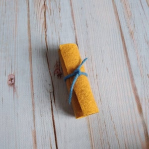 May include: A rolled up piece of yellow felt tied with a blue string.