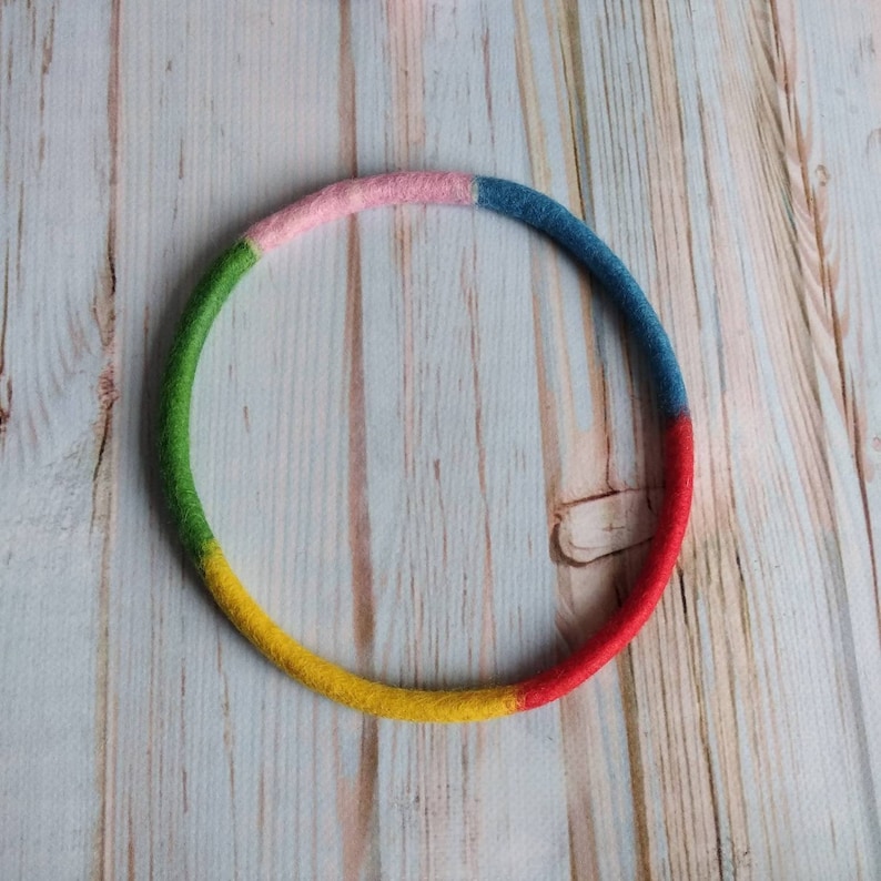 May include: A colorful felt ring with green, pink, blue, and yellow sections.