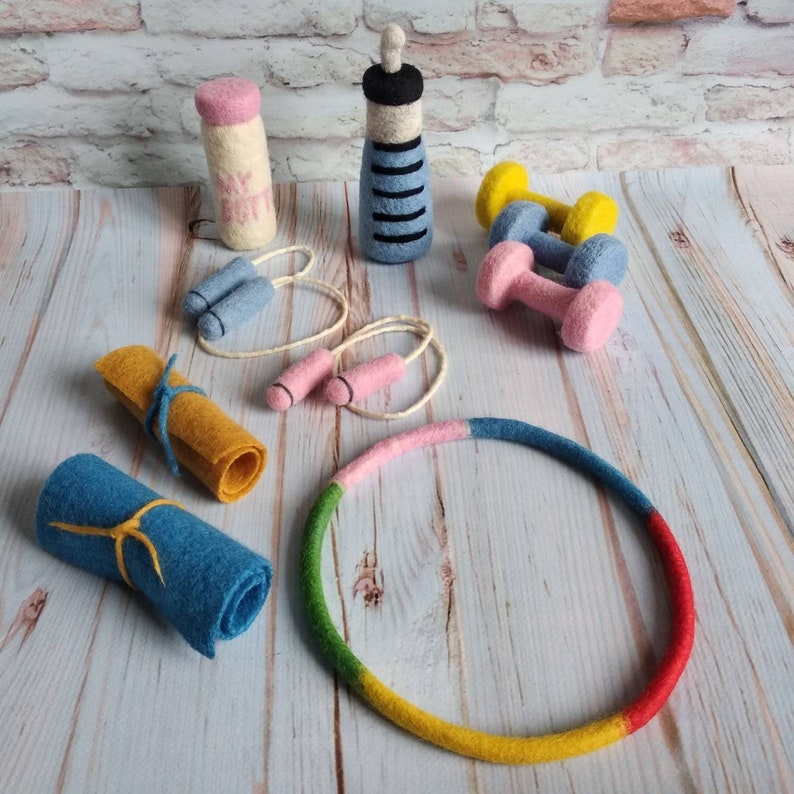 May include: A set of felt toys for children, including a blue and yellow dumbbell, a pink and blue jump rope, a blue and yellow hula hoop, a pink milk bottle, and a blue and white bottle.