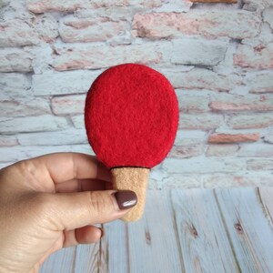 K&ouml;nnte beinhalten: Ein rotes Filz-Tischtennisblatt mit einem braunen Filzgriff.