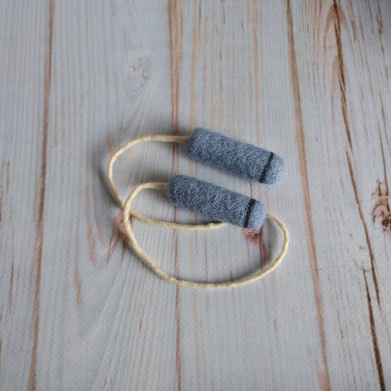 May include: A pair of gray felt jump ropes with a cream-colored string.