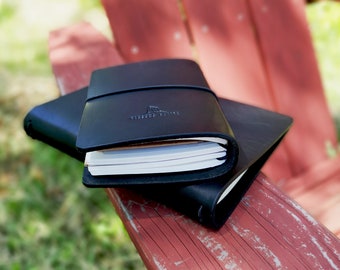 May include: Two black leather-bound journals with a simple design. The top journal has the text "VINTAGE NOTES" embossed on the front cover.