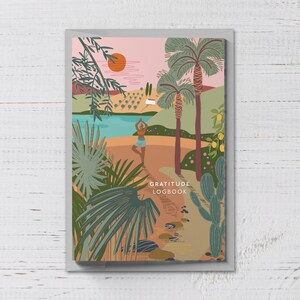 Puede incluir: Un diario con una colorida ilustraci&oacute;n de una escena de playa con palmeras, un lago y una persona haciendo yoga. La portada del diario tiene las palabras "GRATITUDE LOGBOOK" en una fuente sans-serif.