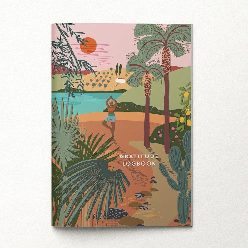 Puede incluir: Un diario con una colorida ilustraci&oacute;n de una escena de playa con palmeras, una persona haciendo yoga y el texto "GRATITUDE LOGBOOK". La portada presenta una puesta de sol, agua y varias plantas.