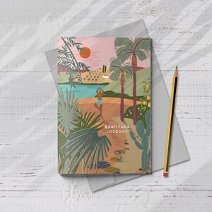 Puede incluir: Un diario de gratitud con una colorida ilustraci&oacute;n de una escena de playa con palmeras, una persona haciendo yoga y el texto "Gratitude Logbook". Un l&aacute;piz amarillo y negro descansa en la esquina.
