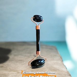 May include: A black jade facial roller with copper-colored metal accents. The roller has two oval-shaped jade stones connected by a black handle. Text on the image reads: Cooling Jade Stone for Facial Massage.