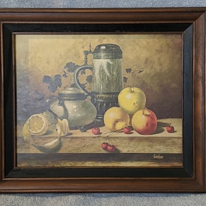 May include: A framed still life painting featuring a silver pitcher, a silver sugar bowl, a lemon, apples, and cherries. The painting is signed "Goetcher" in the bottom right corner.
