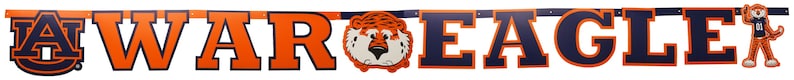 May include: A banner with the words "WAR EAGLE" in orange and navy blue block letters. A cartoon tiger mascot is featured in the center and at the end of the banner. The banner is likely for Auburn University.