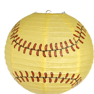 May include: A round, yellow paper lantern designed to resemble a softball. The lantern features red stitching details and a metal wire for hanging. The lantern is a decorative item.