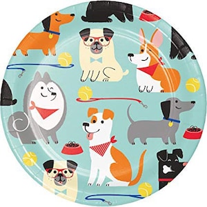 May include: A round, light blue paper plate featuring various cartoon dog illustrations. The dogs are in different breeds and colors, with tennis balls, leashes, and food bowls scattered around the plate.