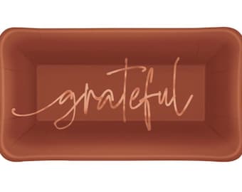 May include: A rectangular terracotta-colored baking pan with rounded corners. The interior base features the word grateful written in a metallic copper-toned cursive script font centered across the bottom surface of the container.