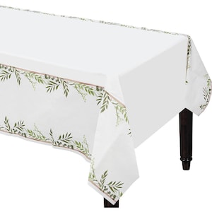 May include: White rectangular tablecloth with a decorative border featuring green leaves and berries. The border is outlined with a thin brown line. The tablecloth is draped over a dark brown wooden table.