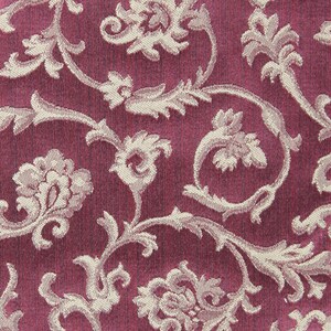 May include: A close-up of a pink fabric with a white floral pattern. The fabric has a textured, woven look.