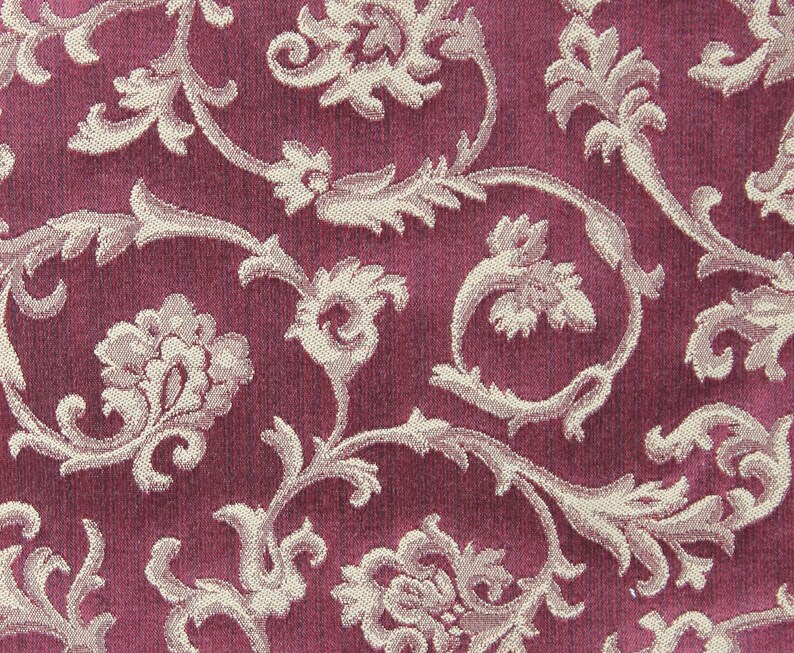 May include: A close-up of a pink fabric with a white floral pattern. The fabric has a textured, woven look.