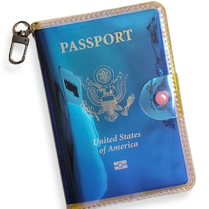 K&ouml;nnte beinhalten: Ein blauer Reisepass-Etui mit einem goldenen Rei&szlig;verschluss und einem transparenten Plastikfenster. Das Etui tr&auml;gt die Aufschrift "PASSPORT" und "United States of America".