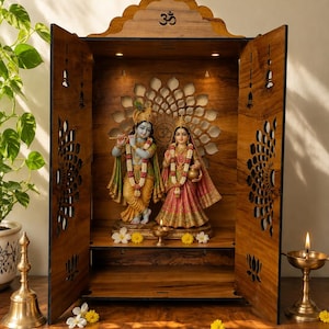 K&ouml;nnte beinhalten: Ein h&ouml;lzerner Heimtempel mit einem Om-Symbol an der Oberseite, filigranen lasergeschnittenen Blumenmustern an den T&uuml;ren und Innenbeleuchtung. Im Inneren stehen Statuen von Krishna mit Fl&ouml;te und Radha auf einem Sockel, erg&auml;nzt durch eine kleine &Ouml;llampe.