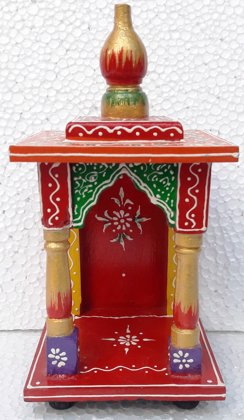 Puede incluir: Un peque&ntilde;o templo de madera pintado a mano con una base roja, acentos verdes y dorados y un remate dorado. El templo tiene un peque&ntilde;o nicho para una deidad o un &iacute;dolo.