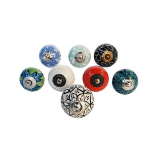 May include: Assortment of eight ceramic knobs with various patterns and colors, including blue, green, red, black, and white. Each knob has a silver metal accent in the center.