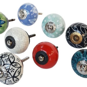 May include: Assortment of eight ceramic cabinet knobs with various floral and geometric patterns. The knobs are in shades of blue, green, white, black, red, and teal. Each knob has a silver metal base.