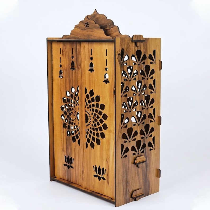 K&ouml;nnte beinhalten: Ein h&ouml;lzerner Heimtempel mit nat&uuml;rlicher Holzmaserung, aufwendigen lasergeschnittenen Lotusblumenmustern auf den Vordert&uuml;ren, Seitenteilen mit f&auml;cherf&ouml;rmigen Ausschnitten, Glockenmotiven und einem in den Bogen geschnitzten Om-Symbol.