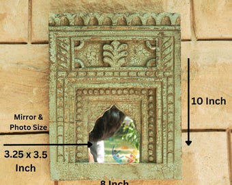 May include: A rectangular wooden wall mirror with a distressed light green finish and carved architectural details. The frame measures 10 inches in height and 8 inches in width, with a central mirror opening measuring 3.25 by 3.5 inches.