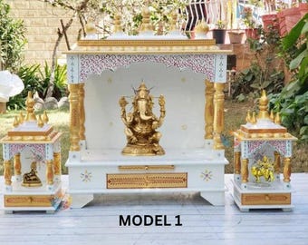May include: A white and gold wooden temple shrine featuring a central Ganesha statue, flanked by two smaller shrines. The structures have ornate gold pillars, decorative red and white patterns, and tiered roofs. The text MODEL 1 is at the bottom.