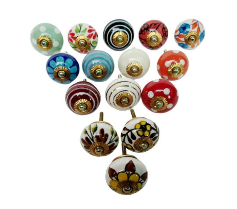 May include: Assortment of 15 ceramic knobs with various patterns and colors, including floral, polka dot, and striped designs. The knobs have a gold-colored metal base.