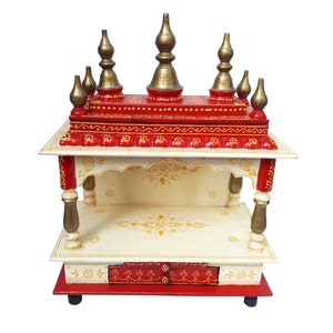 Könnte beinhalten: Ein kleiner, handbemalter Holztempel mit roter Basis, weißen Wänden und goldenen Akzenten. Der Tempel hat eine kleine Schublade und ein Regal im Inneren.