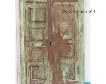 May include: A rectangular wooden window frame with two hinged panels, featuring a distressed light green paint finish over brown wood. The surface shows significant wear and texture. The text WelcomeIndianArt is visible on the right panel.