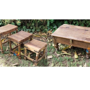 May include: Three wooden nesting tables with a rustic finish. The largest table has a hinged top and a brass latch. The tables are arranged in a staggered formation on a grassy surface.