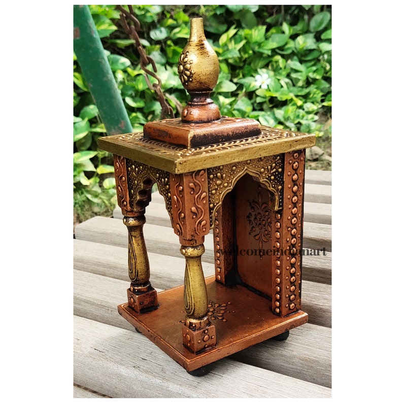 Puede incluir: Un peque&ntilde;o templo de madera adornado con un acabado dorado y cobre. El templo tiene una parte superior decorativa y tallas intrincadas. Est&aacute; dise&ntilde;ado para contener peque&ntilde;as estatuas religiosas u otros objetos.