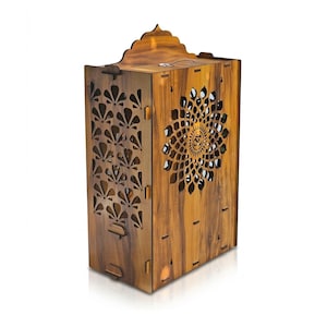 K&ouml;nnte beinhalten: Eine rechteckige R&auml;ucherst&auml;bchenbox aus Holz mit einer nat&uuml;rlichen braunen Holzmaserung. Die Vorderseite zeigt ein lasergeschnittenes Mandalamuster mit einem zentralen Om-Symbol, w&auml;hrend die Seite ein wiederkehrendes f&auml;cherf&ouml;rmiges Design aufweist.