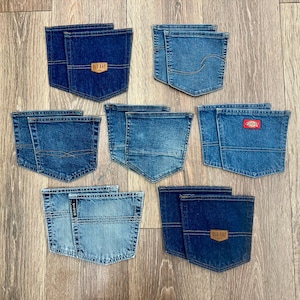 May include: A collection of seven denim pockets in various shades of blue, featuring different stitching patterns and brand labels including Red Kap, Dickies, and Cinch. The pockets are arranged in a grid-like layout, showcasing diverse textures.