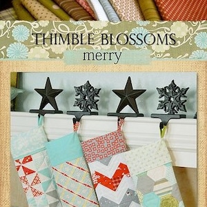 Pode incluir: Quatro meias de Natal com padrões diferentes penduradas em uma lareira. As meias são feitas de tecido e têm uma variedade de cores, incluindo vermelho, branco, azul e verde. As meias são decoradas com padrões diferentes, incluindo um padrão chevron, um padrão geométrico e um padrão patchwork. As meias estão penduradas em uma lareira branca com uma grelha de lareira de metal preto. O texto "THIMBLE BLOSSOMS merry" está impresso acima das meias. O número "#141" está impresso abaixo das meias.