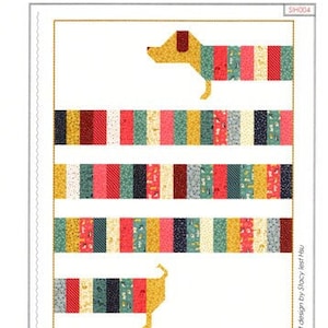 May include: A quilting pattern featuring a dachshund dog made of colorful fabric strips. The pattern is titled "All Wrapped Up" and is designed by Stacy Iest Hsu. The pattern is 45 inches by 60 inches.