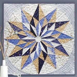 May include: A quilt pattern featuring a large, blue and gold star with a white background. The quilt is titled "Winter Star" and is designed by Brigitte Heitland for Zen Chic.
