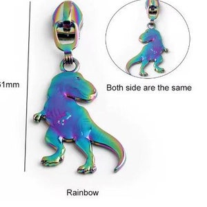 Pode incluir: Puxador de zíper arco-íris iridescente com um design de dinossauro. Ambos os lados do puxador são iguais. O texto "Both side are the same" é visível na imagem. O texto "Rainbow" é visível na imagem.