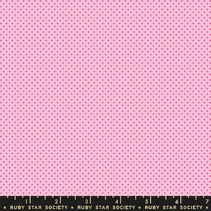 Puede incluir: Una tela de color rosa claro con un patrón repetitivo de pequeños puntos de color rosa oscuro. En el borde inferior, una regla negra muestra medidas de 1 a 7 cm, con el texto Ruby Star Society impreso repetidamente en color dorado.