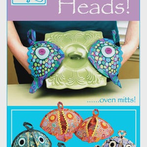 May include: Image of oven mitts with a fish design. The mitts are blue, green, and purple with colorful patterns and large eye details. The image also shows the text "Fish Heads!" and "Vanilla House designs".