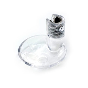 May include: A clear, plastic sewing machine foot with a silver-colored metal top. The foot has a small, clear dish attached. The metal top has a textured, diamond-patterned design.