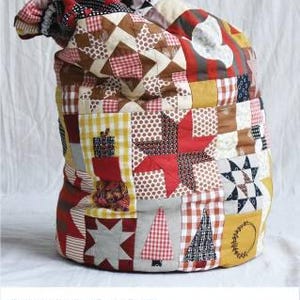 May include: A red, white, and brown patchwork fabric Santa sack with a drawstring closure. The sack is made of various fabrics with different patterns, including stars, polka dots, and plaid. The text "SANTA SACK" is printed below the image. The text "BY JEN KINGWELL PATTERN" is printed below the image.