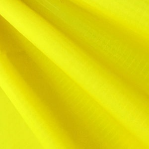 May include: A bright yellow fabric with a smooth texture and subtle folds.