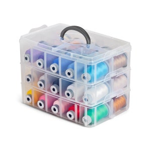 Op de afbeelding: Een transparante plastic opbergdoos met een handvat, verdeeld in compartimenten, gevuld met spoelen gekleurd garen.